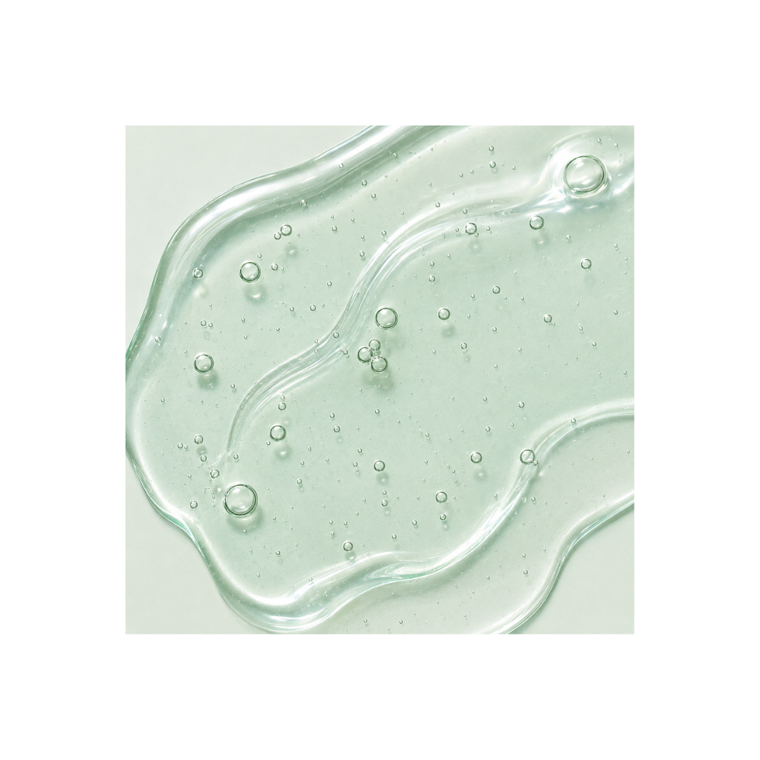 Close-up of a green gel or cream with bubbles on a light green background